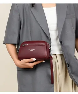 Nahaufnahme der weinroten Handtasche aus Leder mit Litschi-Muster und silbernen Reißverschlüssen