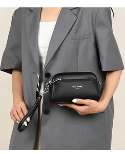 Detail einer schwarzen Clutch aus genarbtem Leder mit Silberreißverschluss und Schlaufe