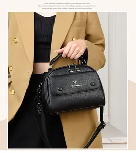 Close-up of black textured leather handbag featuring a gold kangaroo logo and metal nameplate