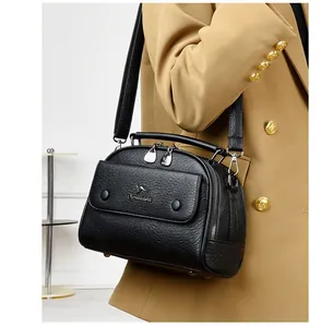Crossbody view of black pebble leather handbag featuring silver hardware on a khaki blazer
