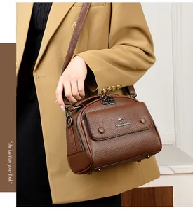 Detail of dark brown leather doctor bag with metal kangaroo logo and crossbody strap