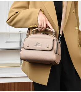 Detailed view of beige leather doctor bag with metal kangaroo logo and crossbody strap