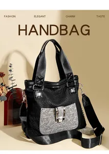 Detail der schwarzen Handtasche mit Metallschließe, breitem Gurt und schicken Anhängern
