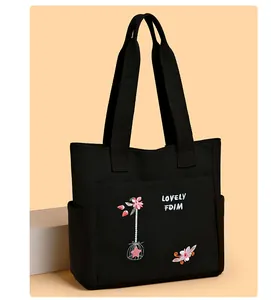 Dettaglio della borsa tote in tela con ricamo di fiori rosa e tasca laterale esterna