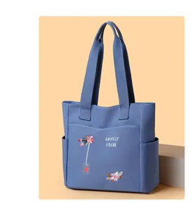 Dettaglio del motivo floreale ricamato e della tasca frontale sulla borsa tote in tela blu