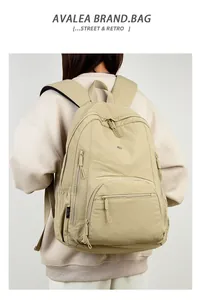Detail view of khaki waterproof backpack with multiple compartments and silver label detail