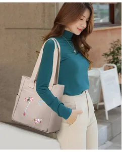 Dettaglio di ricamo floreale e scritta LOVELY FORM sulla borsa tote in tela rosa