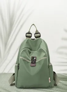 Close-up of lightweight green nylon backpack with silver zipper and decorative logo buckle