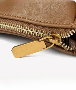 Detailed macro view of the vintage bronze geometric zipper on a brown leather tote bag