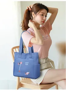 Dettaglio dei ricami floreali e della tasca laterale sulla borsa tote in tela blu
