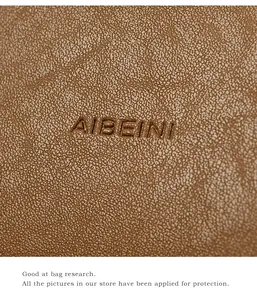 Close-up of the litchi pattern brown leather texture with embossed AIBEINI brand logo