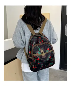 Detail of printed backpack featuring red camo patterns and brown adjustable straps on a model