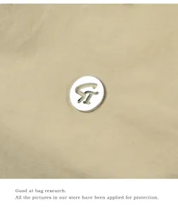 Close-up of a silver metallic ST logo on durable khaki waterproof fabric of a backpack