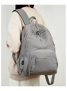 Side view of a large waterproof grey backpack with padded straps on a model