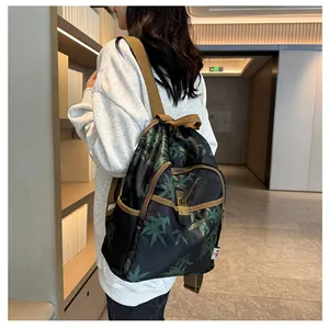 Detail of black backpack with green leaf prints, brown straps and metal buckle closure