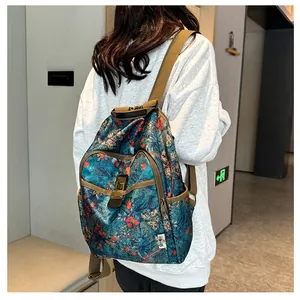 Floral print backpack shown on model featuring blue fabric with red flowers and tan straps