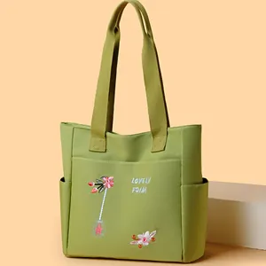 Borsa tote in tela verde con ricami floreali e grande tasca frontale per pendolari