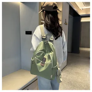 Close-up of a light green nylon backpack featuring a zip pocket and adjustable straps