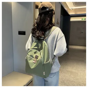 Rear view of a model wearing the green nylon backpack with leather accents in a hallway