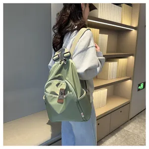 Close-up of a light green nylon backpack with metal logo plate in a library setting