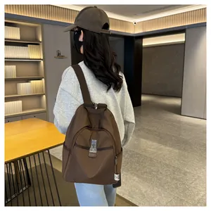 Detail of silver magnetic buckle and zip front pocket on a brown nylon backpack