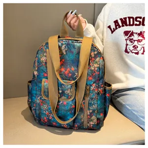 Detail of vintage floral pattern backpack with wide khaki webbing straps on a sofa