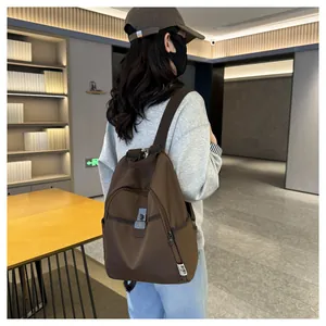 Detail view of a dark coffee waterproof nylon backpack worn by a model in casual setting