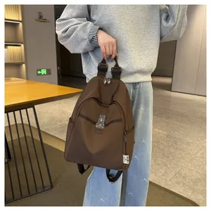 Detail of coffee brown nylon backpack featuring side zipper pocket and metal buckle decor