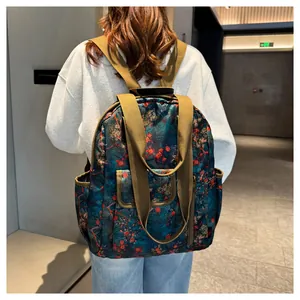 Detailed back view of vintage floral backpack with dark green print and brown straps