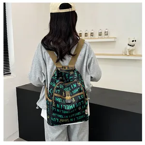 Detail showing the green floral letter print on a stylish black nylon backpack