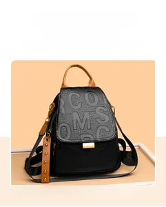 Detail of black pebbled leather backpack with brown straps and gold rivet charm