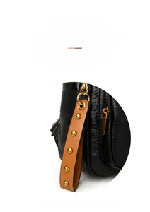 Detail of black pebbled leather bag with brown studded strap and gold metal hardware