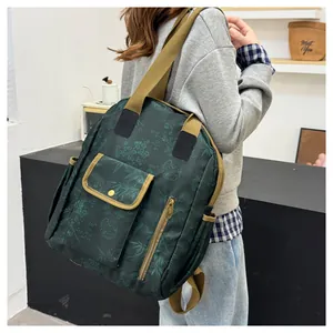 Detail of dark green waterproof backpack with floral patterns and brown fabric straps