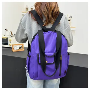 Rear view of a purple waterproof nylon backpack worn indoors for daily use