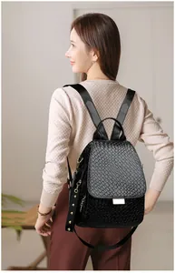Detail of black punk style backpack with woven leather texture and gold buckle accents