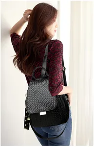 Detail of black punk backpack with rivet accents and snakeskin texture on outdoor model