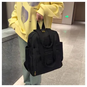 Detailed view of black nylon backpack with multi-pocket design on model in yellow