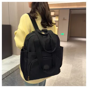 Detail of a large black nylon backpack featuring a front zipper pocket and side pockets