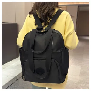 Rear view of a black multi-pocket nylon backpack worn over a yellow sweatshirt