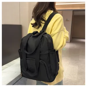 Detail of black nylon backpack featuring front zipper pocket and round logo patch