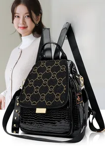 Detail of crocodile embossed backpack with golden interlocking rings and monogrammed trim