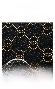 Detail of interlocking golden crystals on black suede with shiny crocodile pattern finish