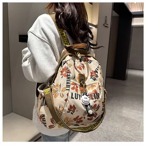 Détail du sac à dos aux motifs floraux colorés avec bretelles tissées et pendentif sourire