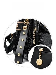 Detail of crocodile texture black bag with gold rivets and floral patterned strap