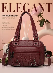 Close-up of deep red leather satchel with woven trim and metallic buckle accents