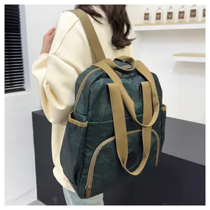 Detail view of the green leaf print backpack featuring khaki canvas straps and pockets
