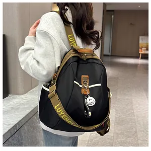 Détail du sac à dos en nylon noir et vert olive avec charm visage souriant sur le côté