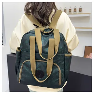 Detail of green floral printed backpack with beige webbed handles and leather logo patch