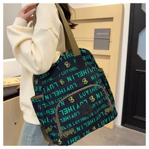 Detail of trendy letter print backpack with green wide strap on model's shoulder