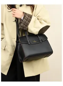 Dettaglio del logo a canguro dorato sulla borsa a mano in pelle nera testurizzata